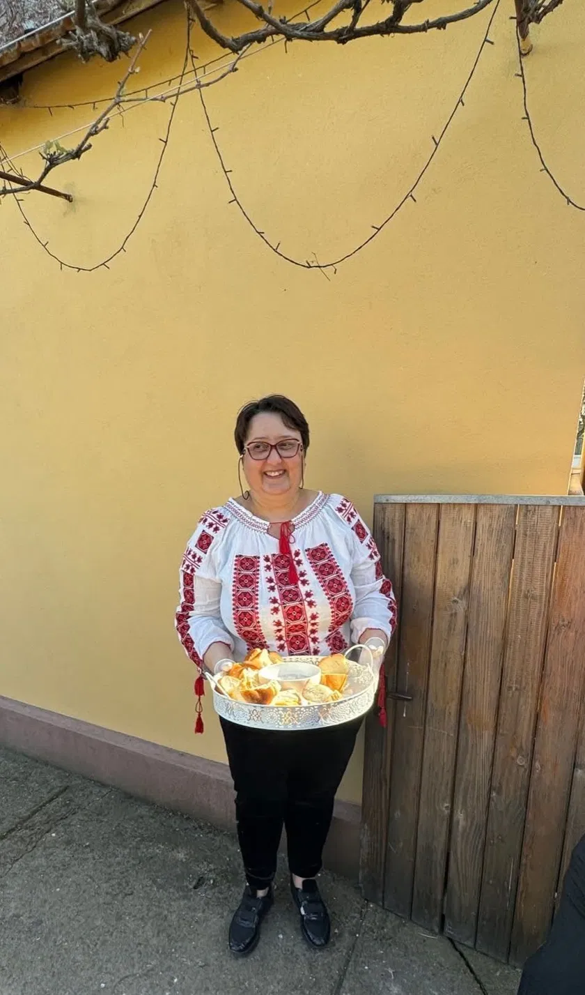 Bunica în ie tradițională românească, cu cozonaci proaspeți, la Casa Bunicilor Ferendia